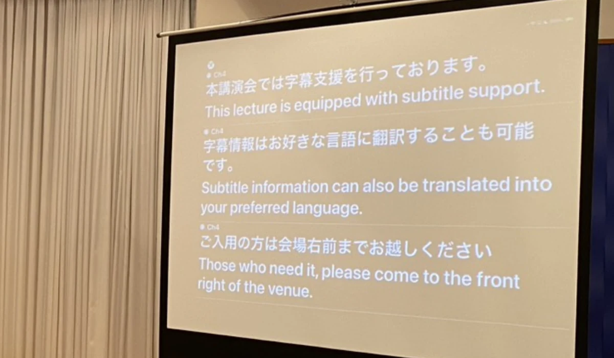 会場スクリーンに字幕と翻訳を表示している様子