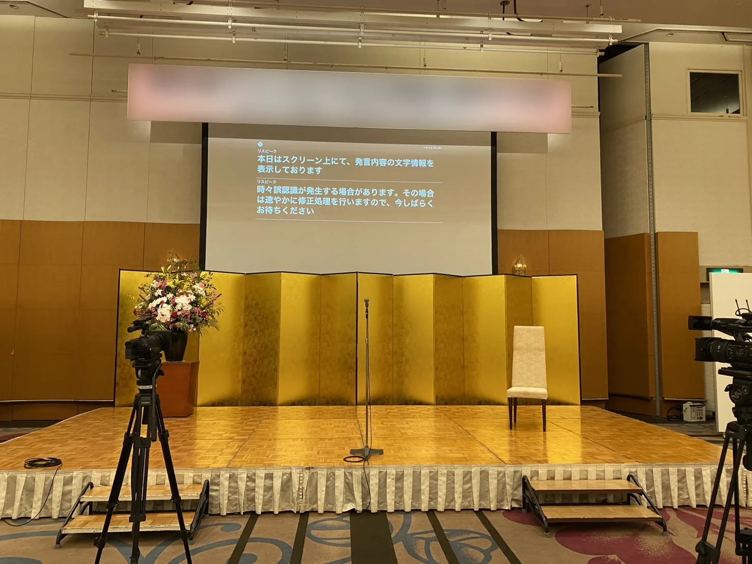 報告会・パーティ会場で発言内容を字幕表示している様子